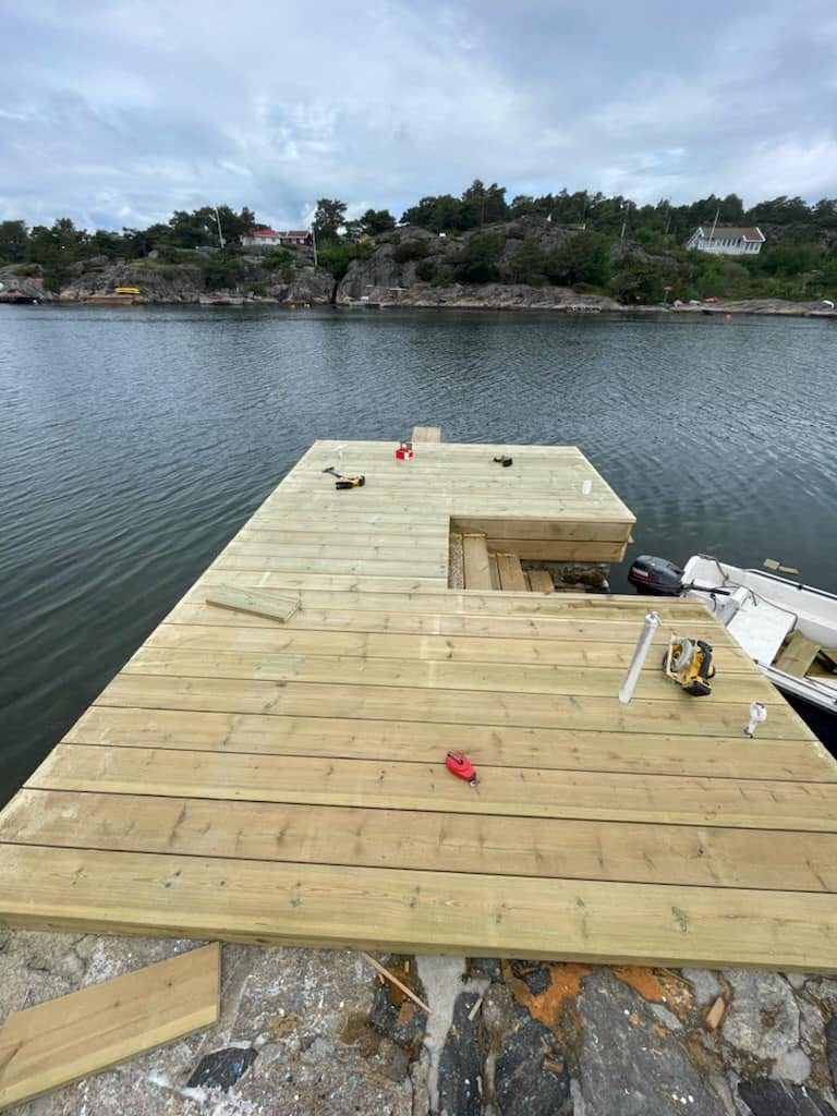 Ny brygge i lyst trykkimpregnert tre under bygging i skjærgården