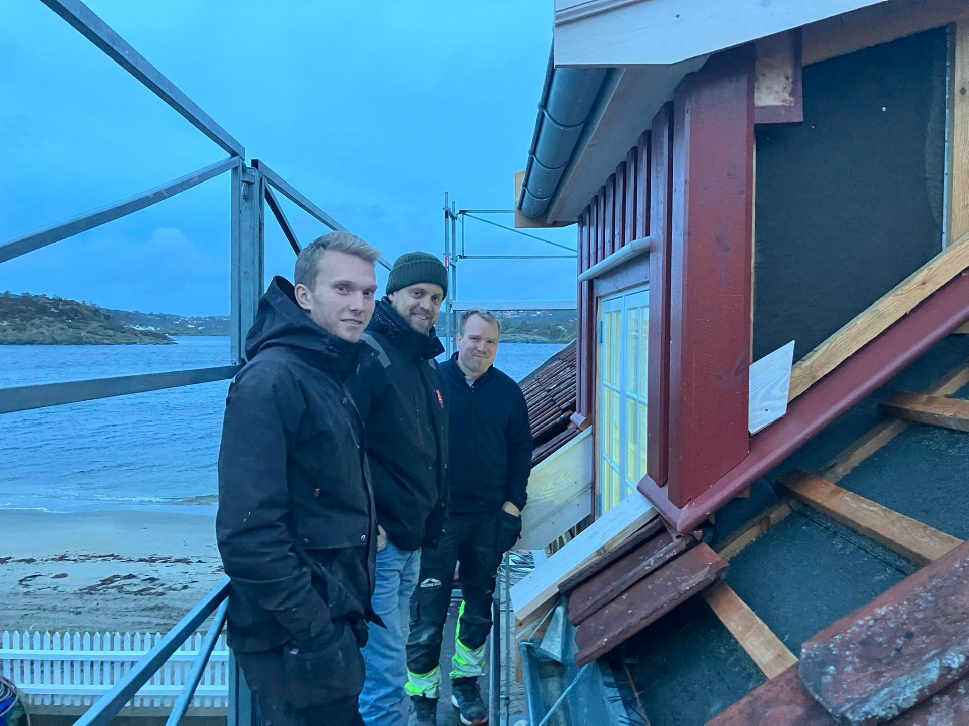 Tømrere fra Viga Bygg AS på stillas ved et sjønært bygg i Arendal