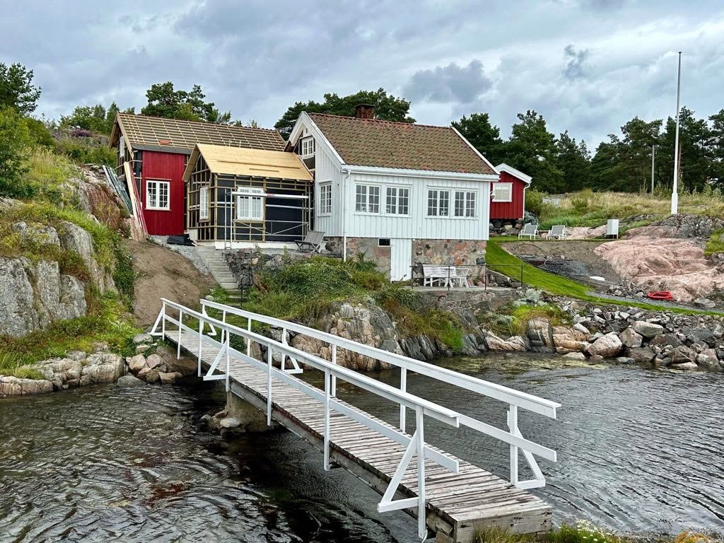 Strandeiendom med nytt tilbygg under oppføring ved brygge og svaberg